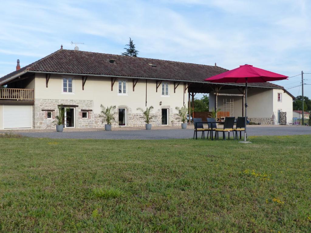 una casa con tavolo e ombrellone rosso di Gites Domaine de la Rochere a Domsure