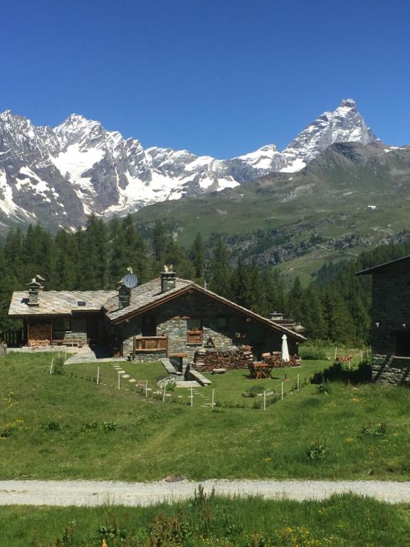 una casa in un campo con montagne sullo sfondo di CHALET GORRET CHENEIL a Valtournenche