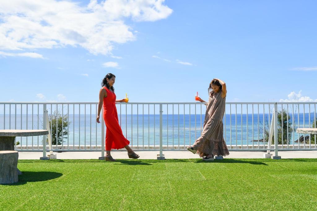 two women walking along a fence near the ocean at Odysis Onna Resort Hotel in Onna