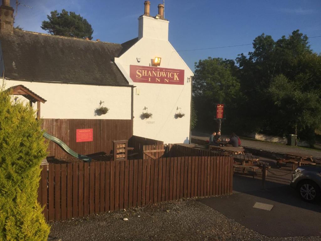 een wit gebouw met een bord aan de zijkant bij The Shandwick Inn in Tain