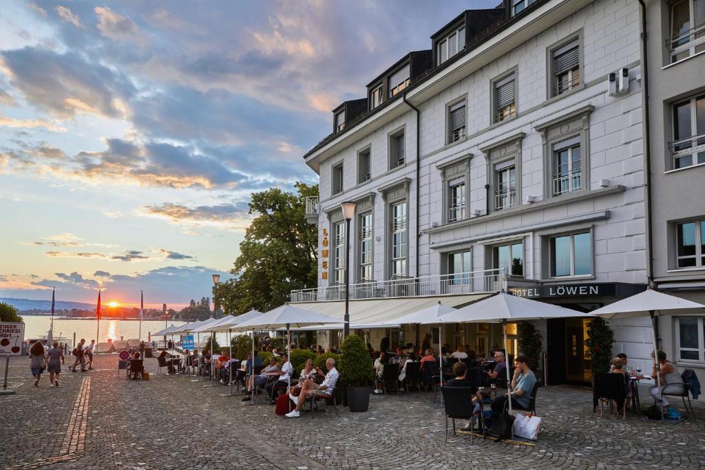 people sitting at tables outside of a building at Hotel Löwen am See in Zug