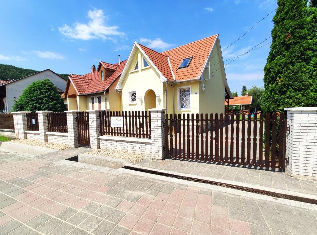 une maison jaune avec une clôture en bois dans l'établissement Apollo Vendégház, à Bogács