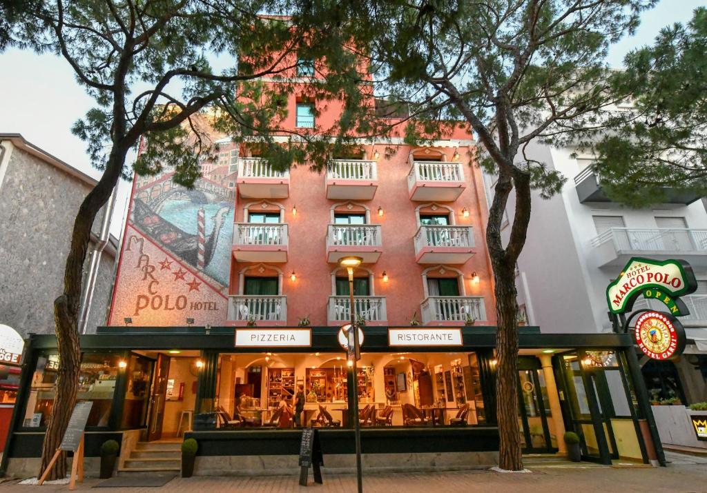 um edifício numa rua com árvores em frente em Hotel Marco Polo em Lido di Jesolo