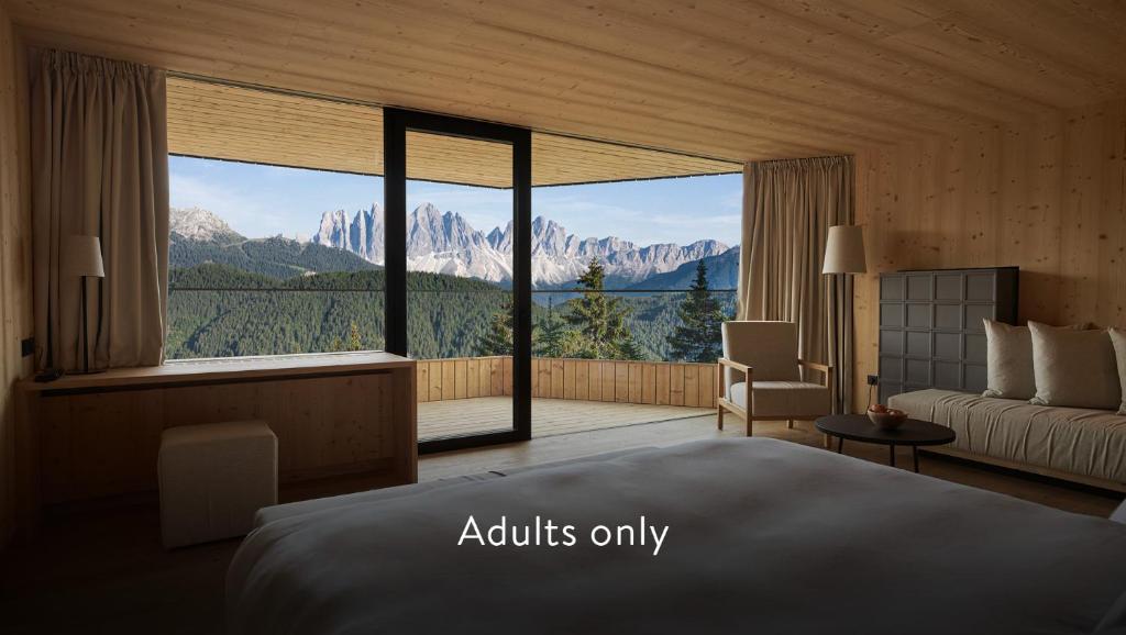 een slaapkamer met een bed en een groot raam bij Forestis Dolomites in Bressanone