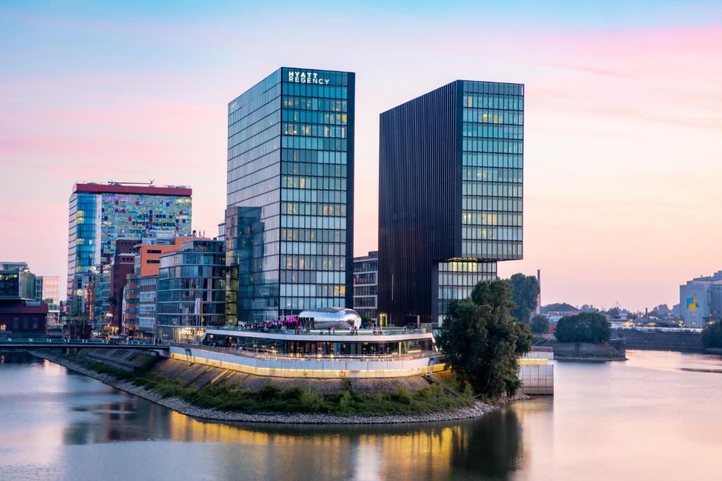 ein Boot auf einem Fluss in einer Stadt mit hohen Gebäuden in der Unterkunft Hyatt Regency Dusseldorf in Düsseldorf