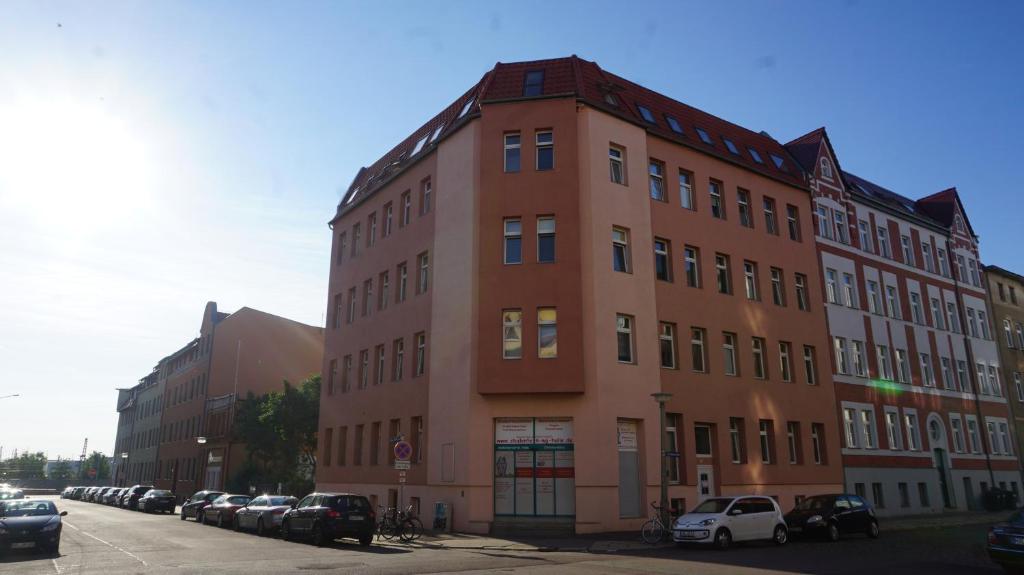 a tall brick building with cars parked in a parking lot at Hostel im Medizinerviertel in Halle an der Saale