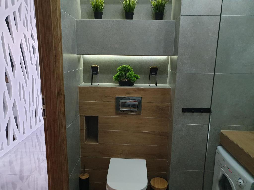 een badkamer met een toilet en planten aan de muur bij Apartament Wrocław Centrum Dorzecze Legnickiej in Wrocław