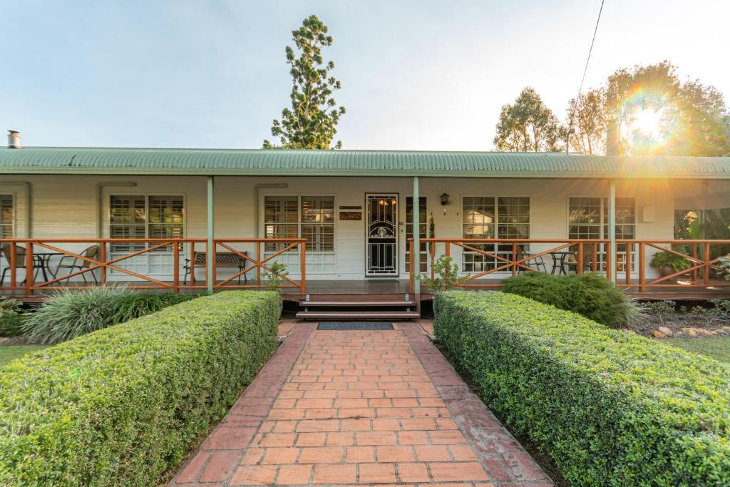 a house with hedges in front of it at Birds 'n' Bloom Cottages in Yungaburra