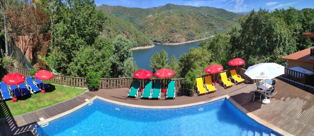 - une piscine avec des chaises longues et des parasols à côté d'une rivière dans l'établissement Casa Encosta do Gerês-Ferias no Gerês, à Vieira do Minho