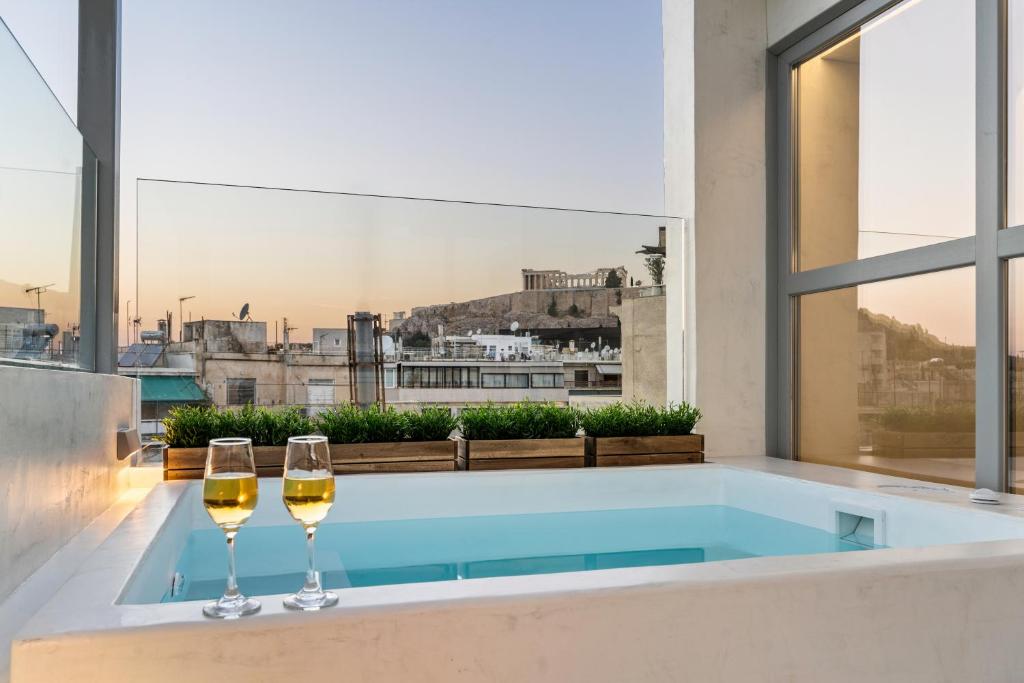 2 bicchieri da vino seduti su una vasca da bagno con vista di ACRON suites & apartments ad Atene