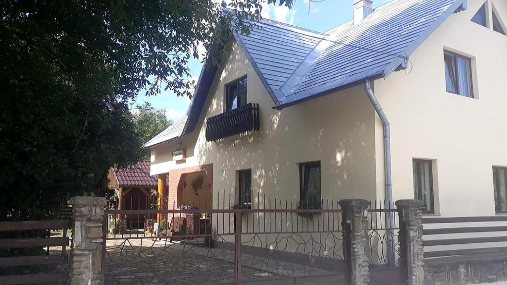 a white house with a blue roof and a fence at Pensiunea Casa Domniței Sucevița in Suceviţa