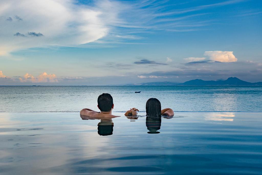 dos personas sentadas en el agua en la playa en Maison Dedine- SmallLuxuryHotels -Adults Only, en Sidi Bou Saïd