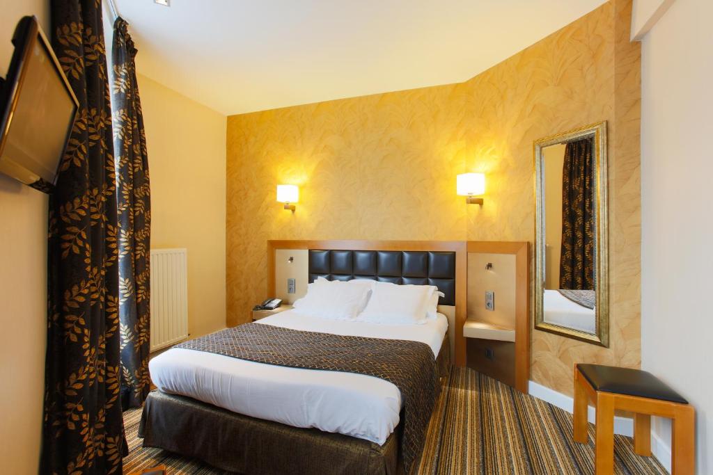 a hotel room with a large bed and a mirror at Hotel Bellevue Saint-Lazare in Paris