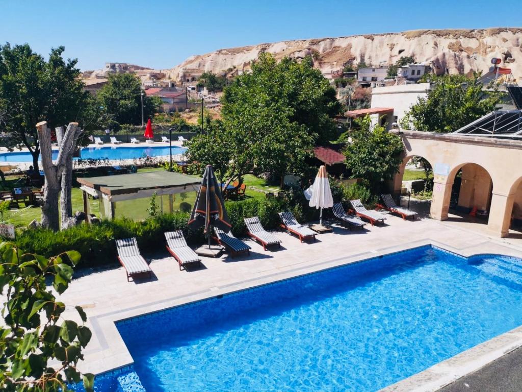 een zwembad met stoelen en parasols naast een resort bij Melis Cave Hotel in Urgup