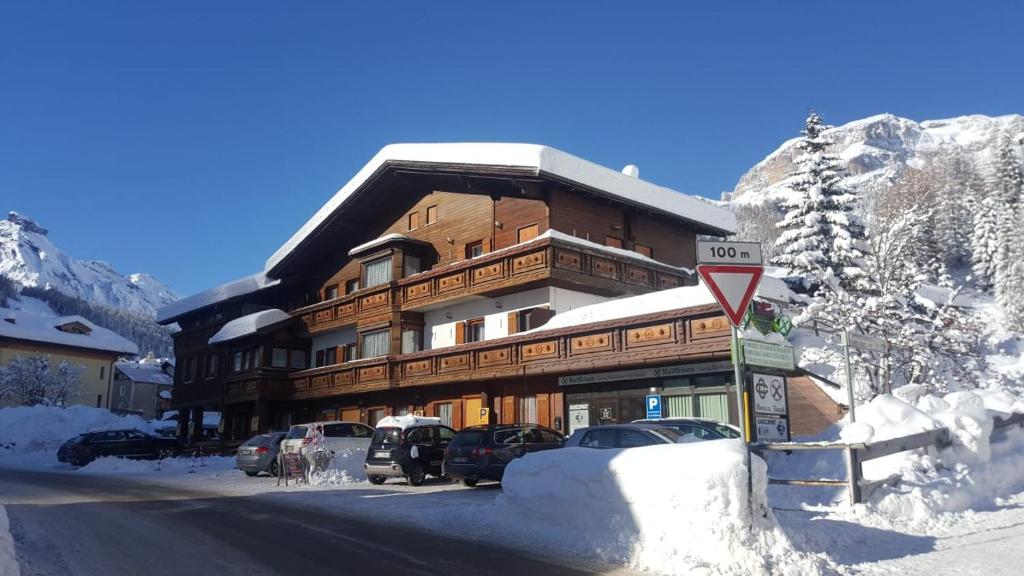 een groot gebouw met auto's geparkeerd in de sneeuw bij Chalet Helen in Arabba