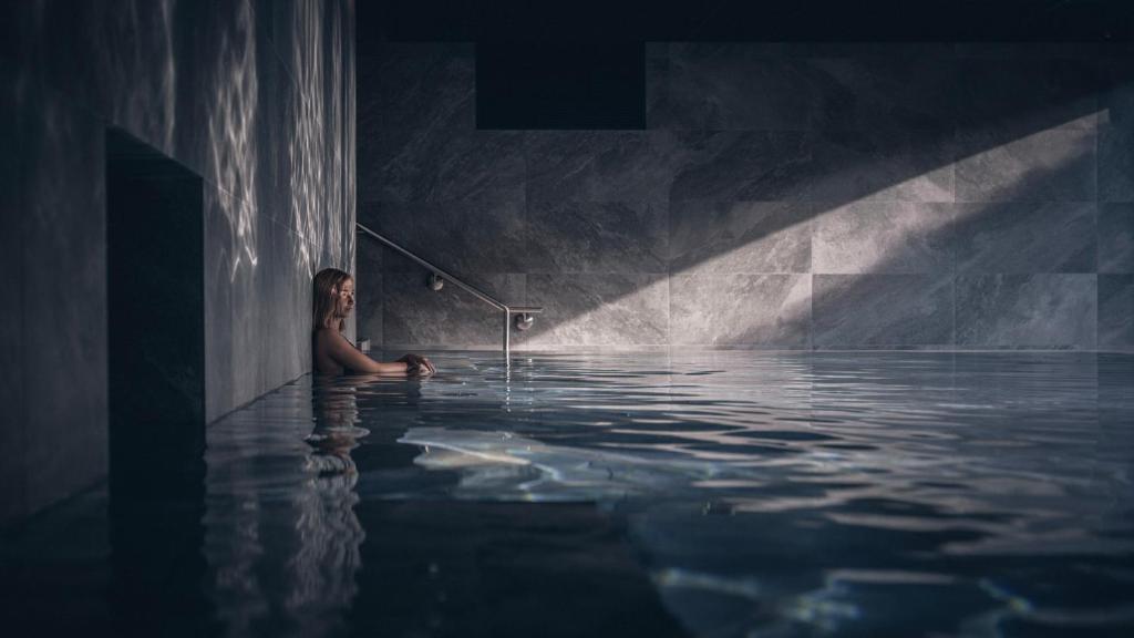 un homme dans un bassin d'eau avec une barre dans l'établissement Le Parc Hôtel Obernai & Yonaguni Spa, à Obernai