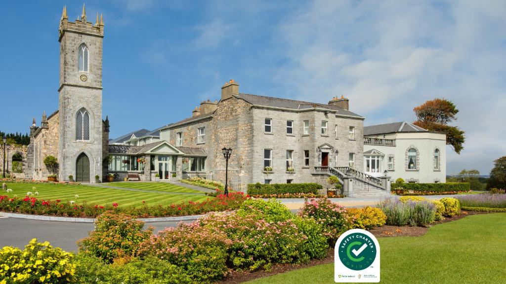 un grande edificio in pietra con torre dell'orologio di Glenlo Abbey Hotel a Galway