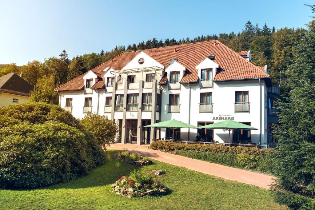 un gran edificio blanco con sombrillas verdes delante en Aktivhotel Inselsberg, en Tabarz