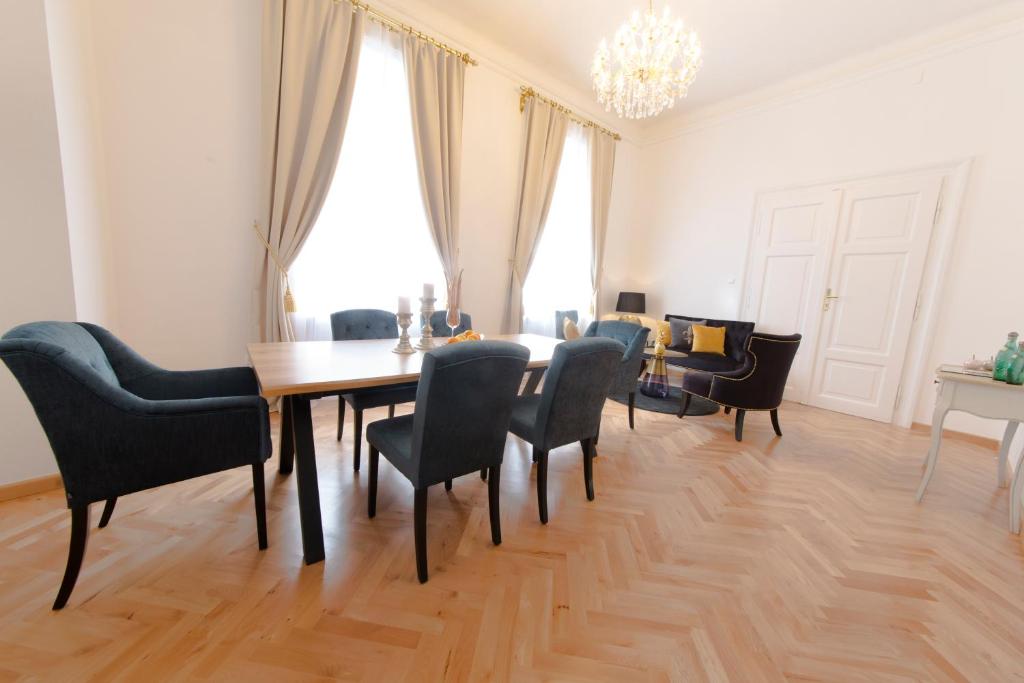 une salle à manger avec une table, des chaises et un lustre dans l'établissement Palais Gutenberg la Ville, à Klagenfurt am Wörthersee