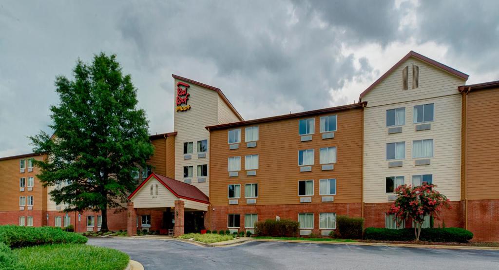 Red Roof Inn PLUS Raleigh Downtown NCSU Conv Center في رالي: مبنى الفندق امامه شجرة