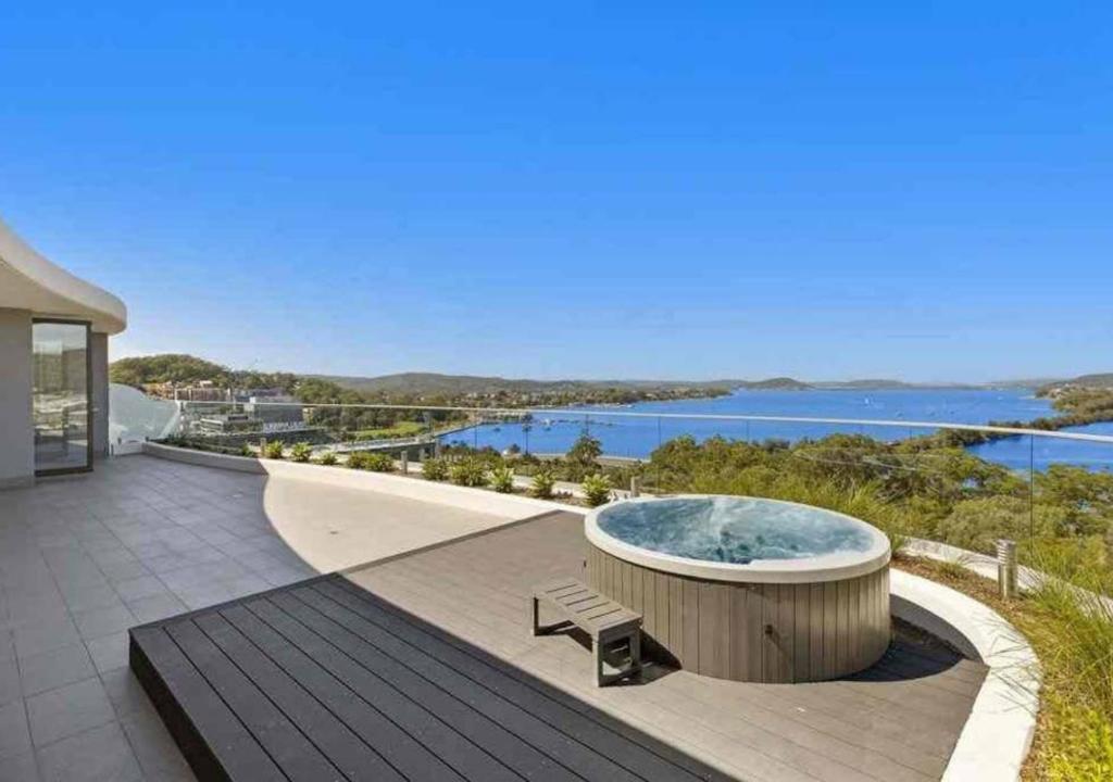 einen Whirlpool auf einer Terrasse mit Blick auf das Wasser in der Unterkunft Stylish Penthouse with Views & Jacuzzi in Gosford