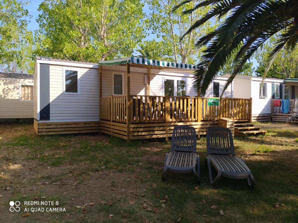 uma casa com duas cadeiras em frente em Mobile Homes by KelAir at Playa Montroig Camping Resort em Tarragona