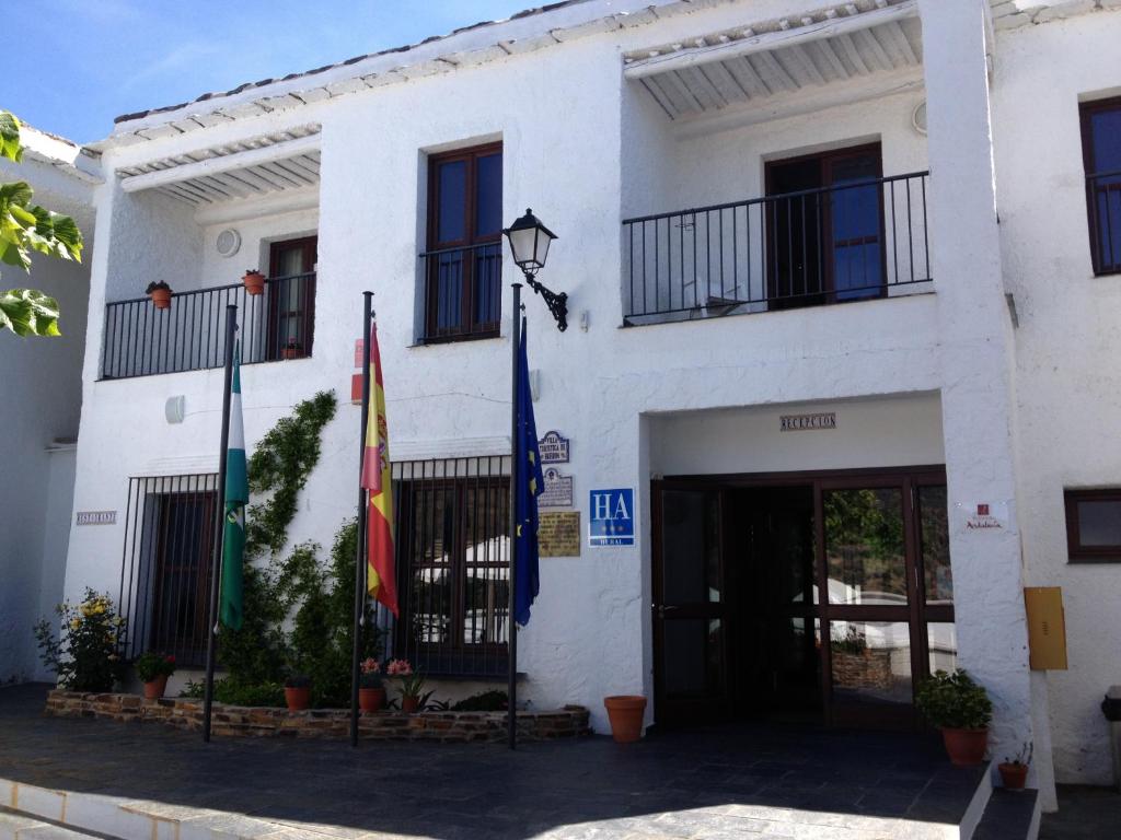 a white building with flags in front of it at Villa Turistica de Bubion in Bubión