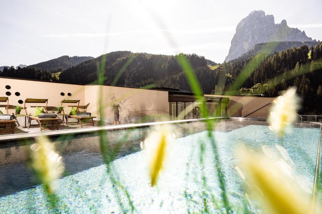 vista su una piscina con montagne sullo sfondo di Hotel Touring Dolomites a Santa Cristina in Val Gardena