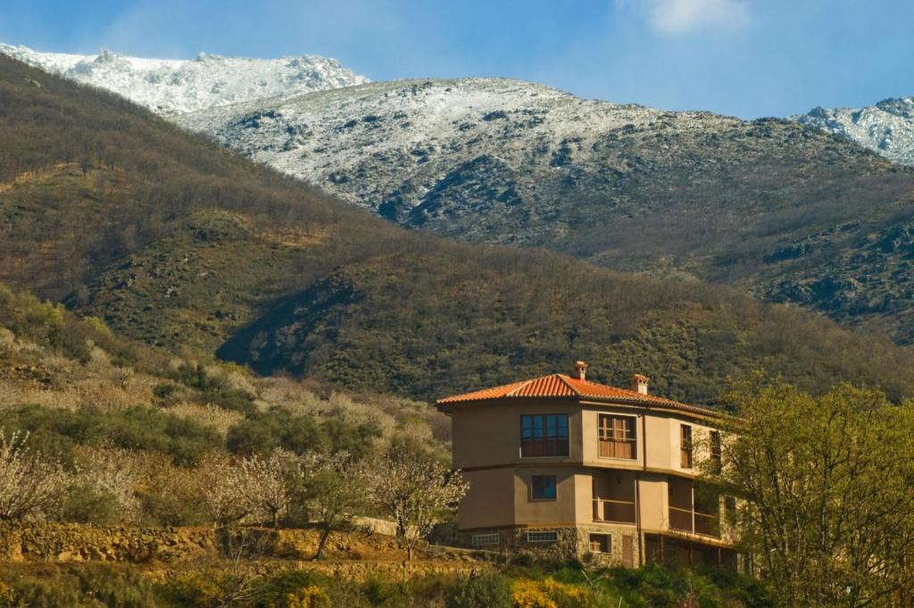 a house on a hill with mountains in the background at Complejo Rural Las Palomas in Jerte