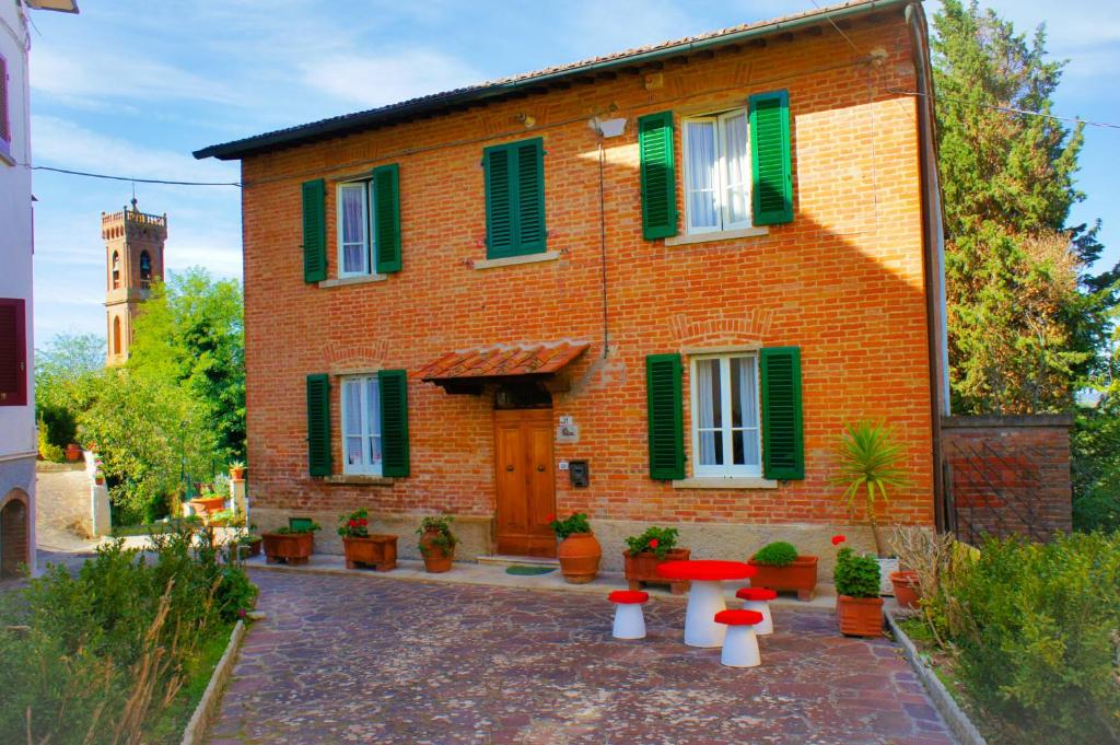 una casa in mattoni con persiane verdi e tavoli di fronte ad essa di Casa Fonte di Bacco a San Miniato