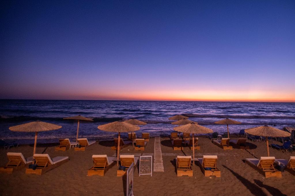 una playa con sillas y sombrillas y el océano en Romantic Palace Beach Apartments, en Agios Gordios