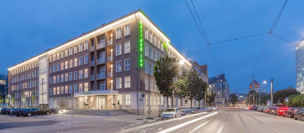 Holiday Inn Dresden - Am Zwinger, an IHG Hotel في درسدن: مبنى كبير على شارع المدينة فيه سيارات متوقفة