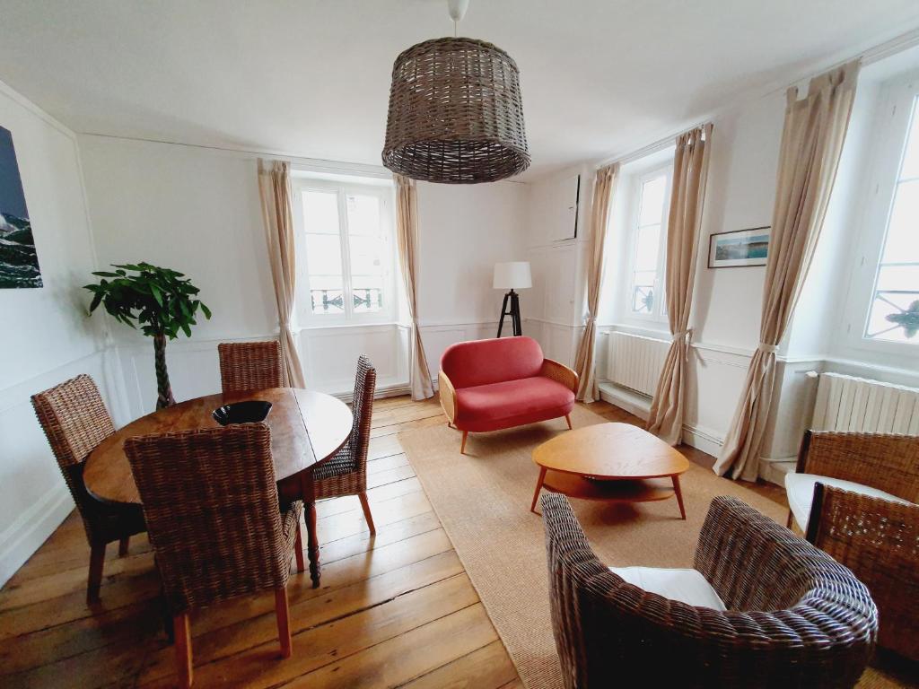 een woonkamer met een tafel en stoelen en een rode stoel bij Les Sablons - Très Bel Appartement , Lumineux in Saint-Malo