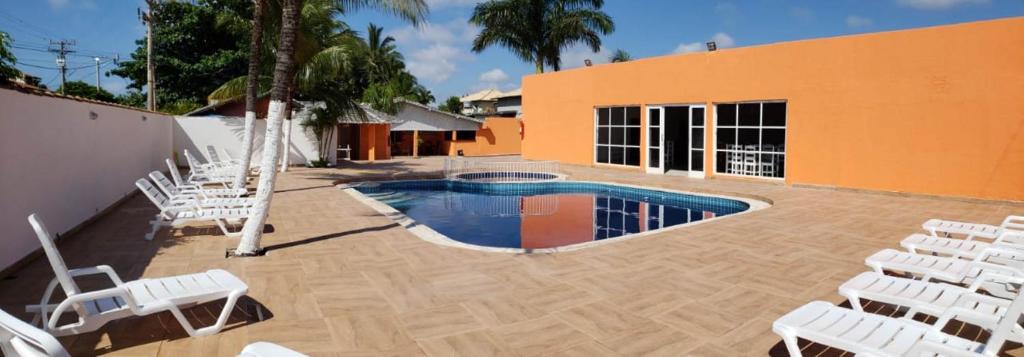 een groep stoelen en een zwembad met een aantal zitjes bij Villa Solarium Pousada in Cabo Frio