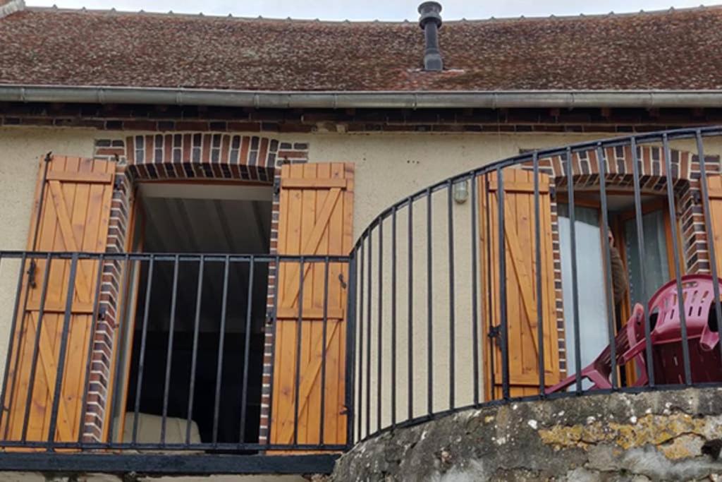 una casa con porte in legno e balcone di le rempart a Saint-Julien-du-Sault