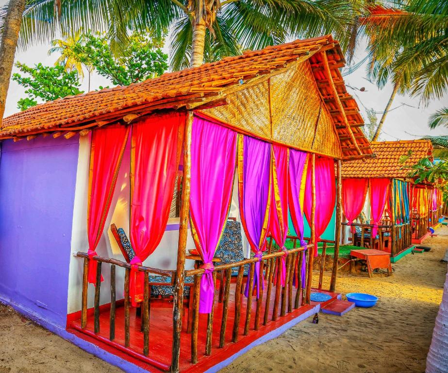 een klein huis met kleurrijke gordijnen op een strand bij GoYm Resort in Arambol