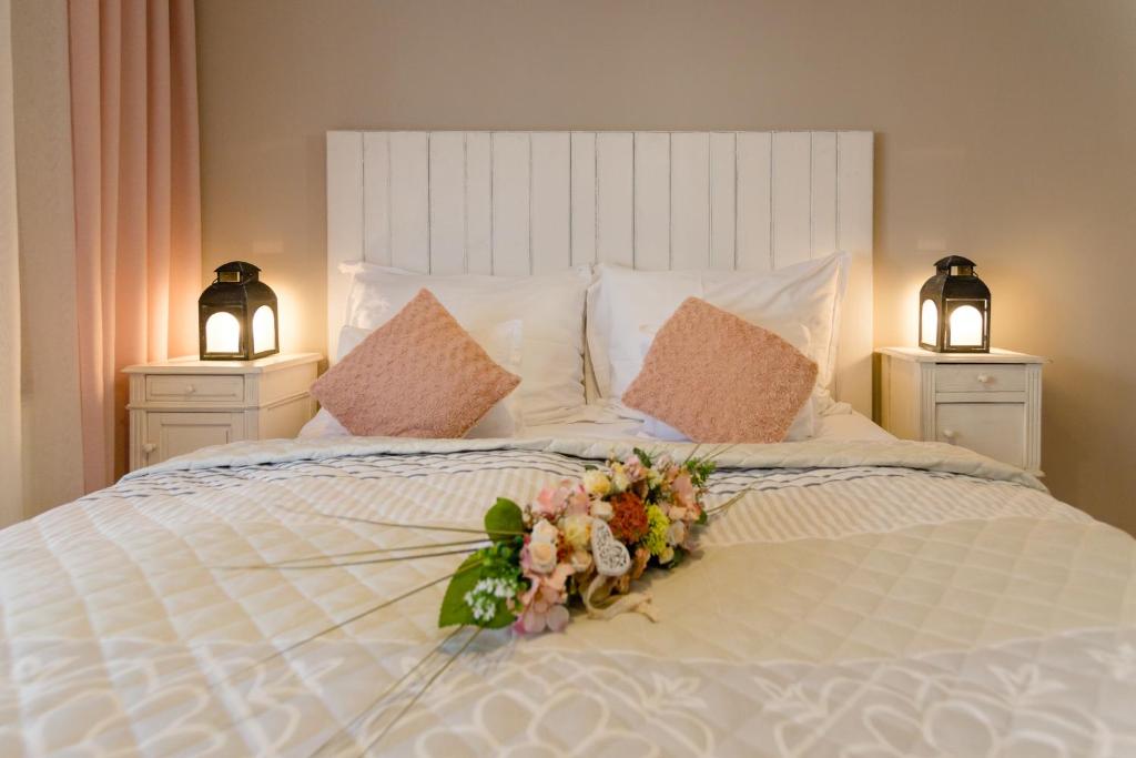 a white bed with a bouquet of flowers on it at Aurora Vendégház in Hévíz