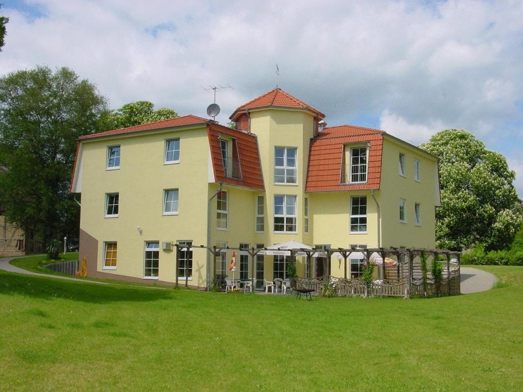 uma grande casa amarela com um telhado laranja em Landhotel Am Peetscher See em Mirow