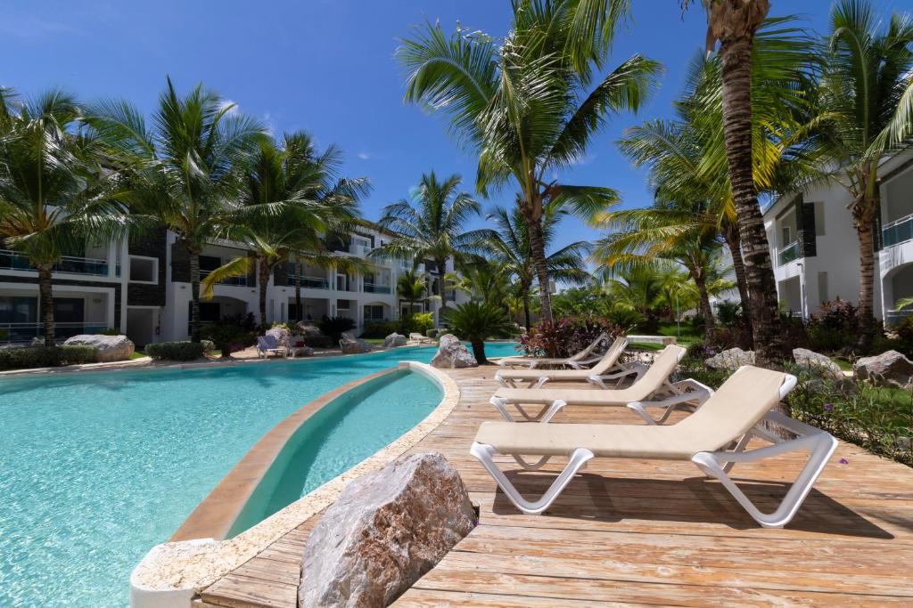 uma piscina de resort com espreguiçadeiras e palmeiras em Atmospheric apartment with a beautiful view of the swimming pool em Bayahibe