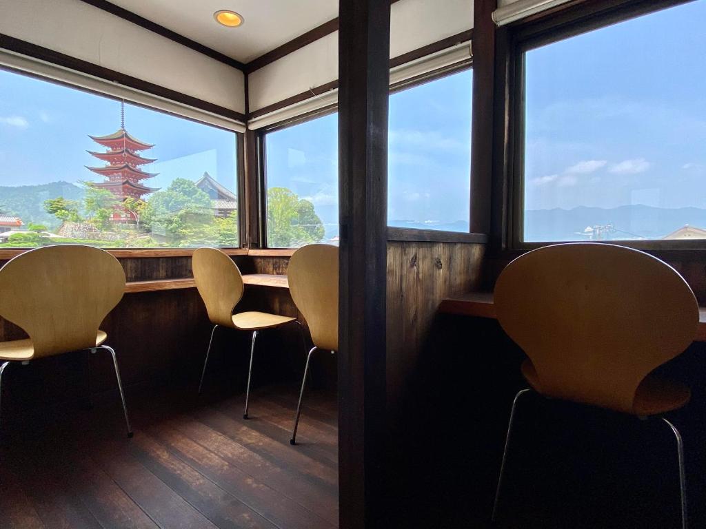 een kamer met stoelen, een tafel en ramen bij Ryoso Kawaguchi in Miyajima