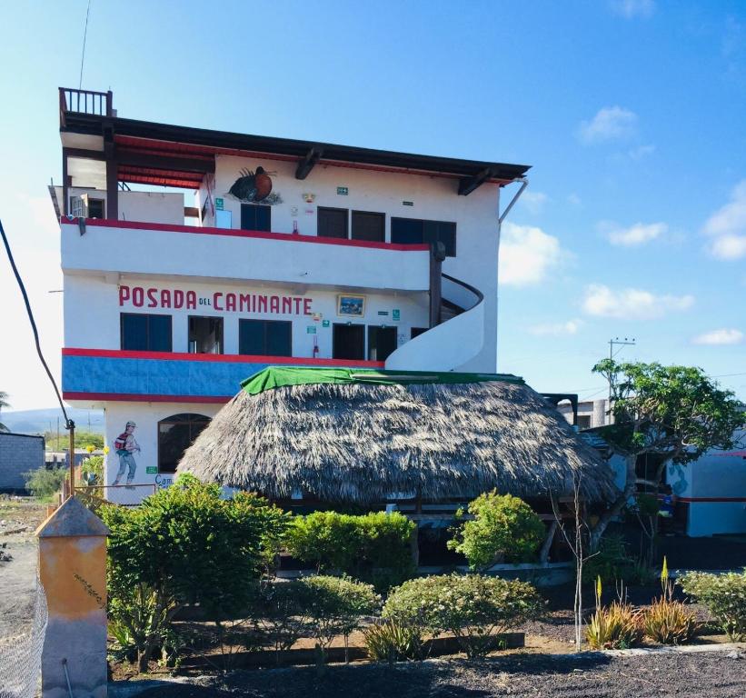 a building with a thatch roof in front of it at Posada del Caminante in Puerto Villamil