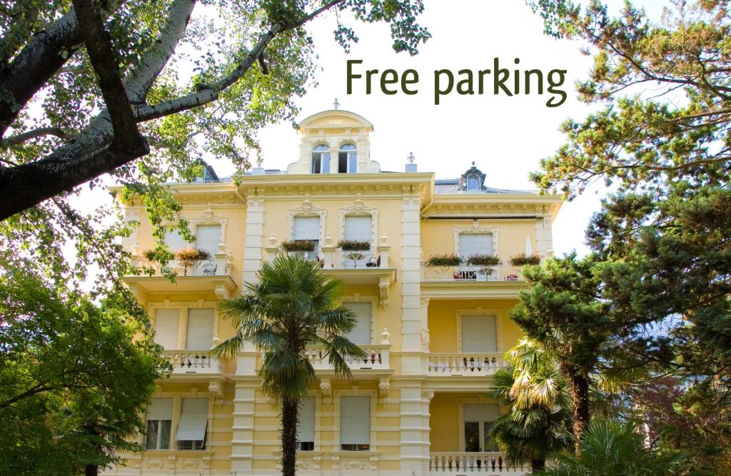 un edificio giallo con le parole parcheggio gratuito di Hotel Villa Westend a Merano