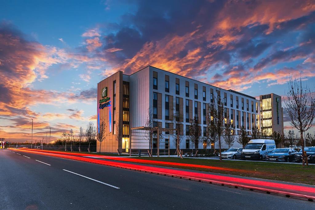 un edificio al lado de una carretera con una puesta de sol en Holiday Inn Express - Bicester, an IHG Hotel, en Bicester