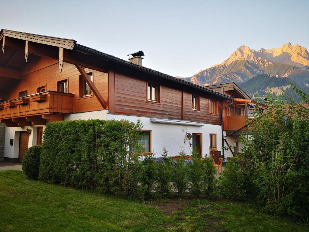 una grande casa in legno con montagne sullo sfondo di Haus Luxgütl a Saalfelden am Steinernen Meer