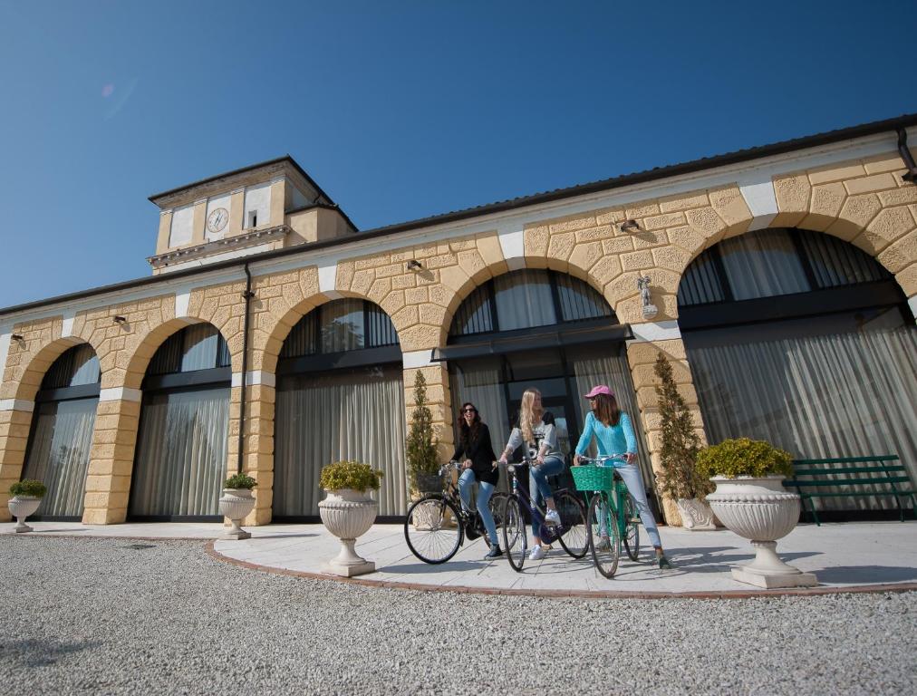 three women riding bikes in front of a building at Residence Cà Beregana in Vicenza