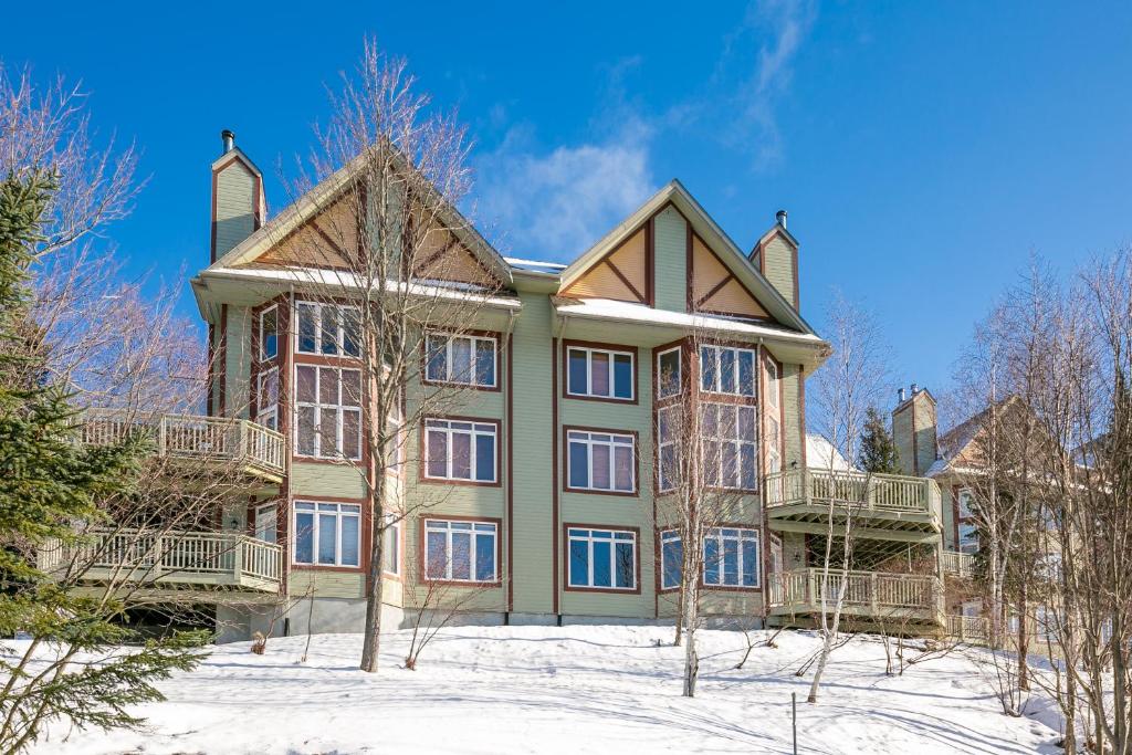 una grande casa con la neve davanti di Le Chalumeau by Chez Tremblant a Mont-Tremblant