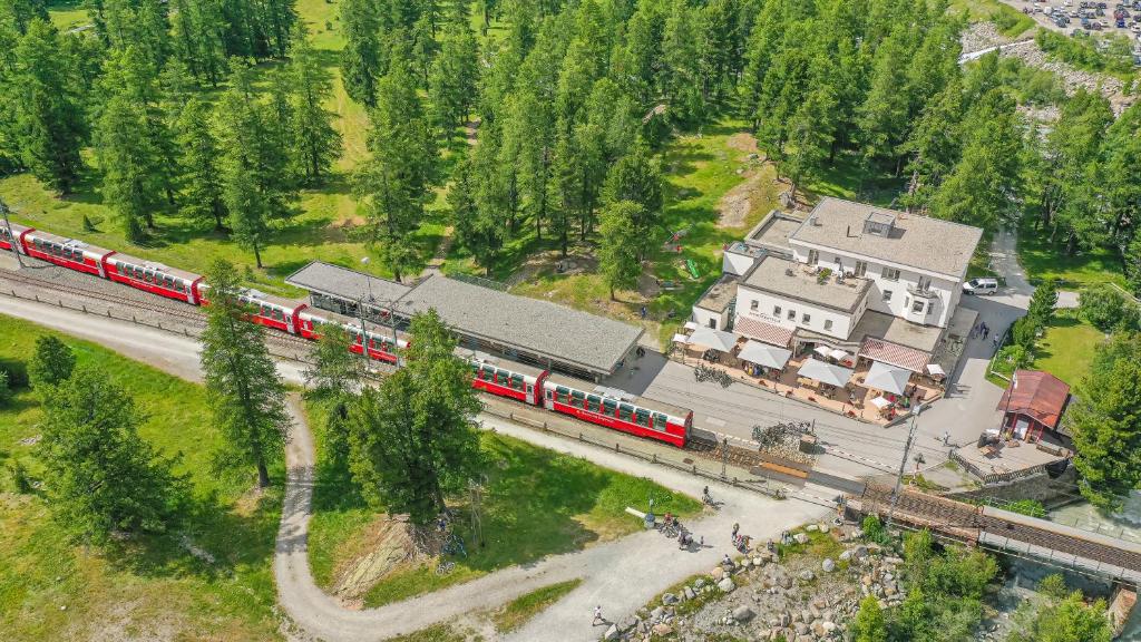 un tren rojo está en las vías cerca de una casa en Hotel Morteratsch, en Pontresina