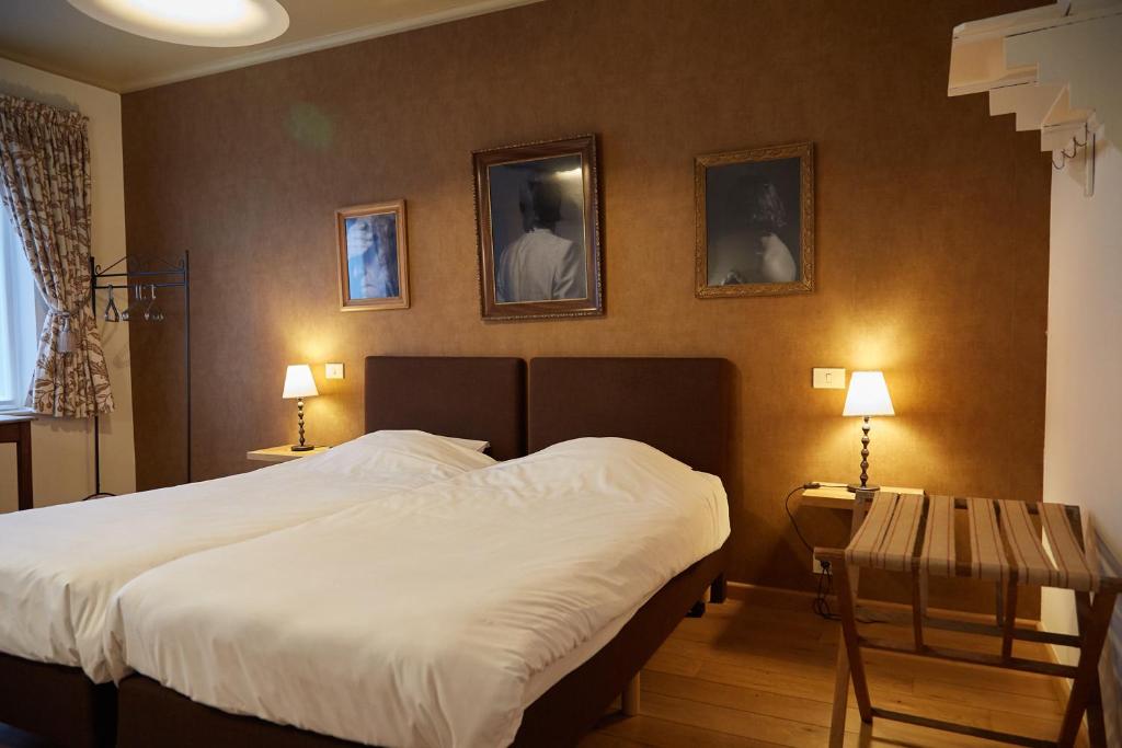 ein Schlafzimmer mit einem Bett und zwei Tischen und zwei Bildern an der Wand in der Unterkunft Focus Hotel in Kortrijk