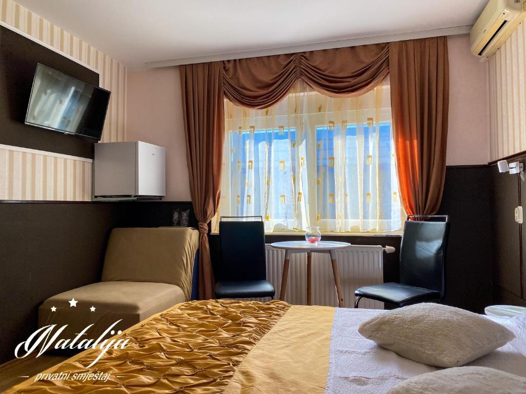 Habitación de hotel con cama, mesa y sillas en Smještaj Natalija, en Osijek