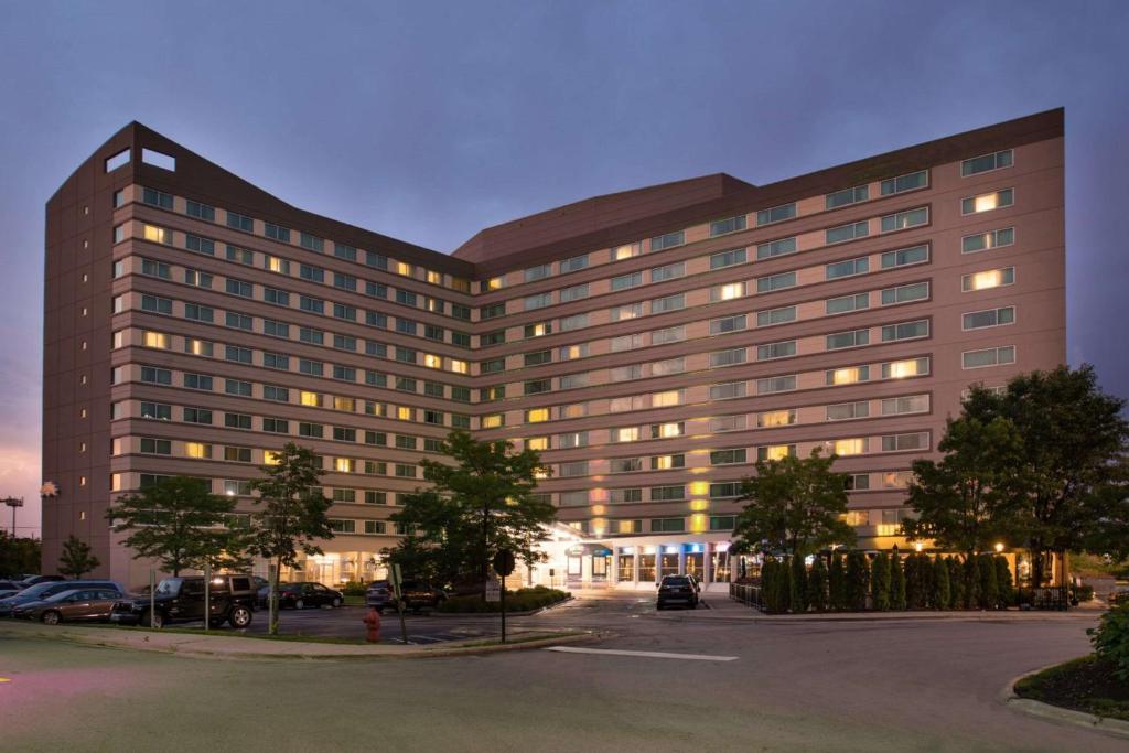 a large building with many windows in a parking lot at Sonesta Chicago O'Hare Airport Rosemont in Rosemont